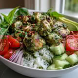 Close-up of Pesto Chicken Bowl featuring juicy chicken, vibrant basil pesto, and a colorful medley of diced cucumbers and red onions.