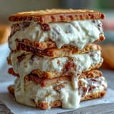 Milk cookie sandwich cookies with cream filling, golden-edged and stacked on a dessert plate.