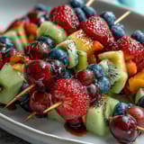 Colorful fruit skewers arranged in rainbow order, paired with a luscious honey and vanilla yogurt dip for a refreshing snack.