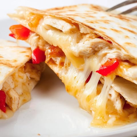 A close-up of a crispy Chicken Quesadilla with grilled chicken and onions on a rustic plate.