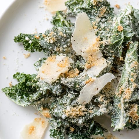Garlic Parmesan Kale Salad served as a vibrant side or light lunch, garnished with shaved Parmesan and fresh black pepper.  