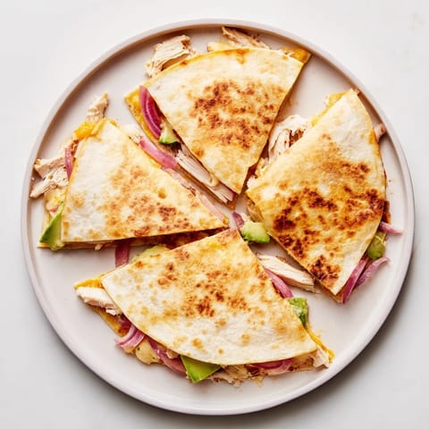 Grilled chicken and creamy avocado mash filling inside a crispy, golden-brown quesadilla, garnished with fresh cilantro.