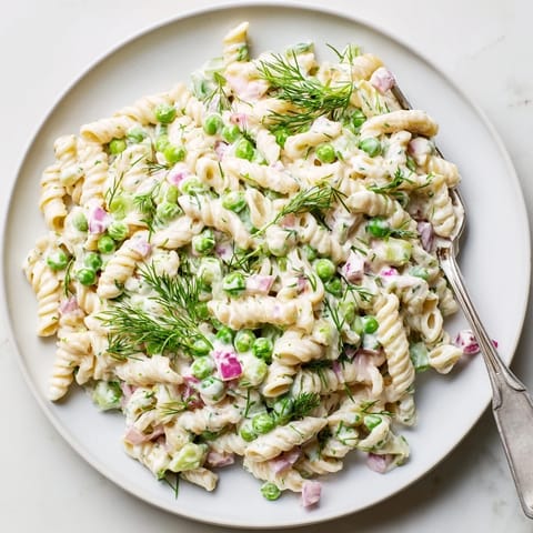A vibrant bowl of Creamy Dill Pickle Pasta Salad featuring ditalini, peas, and crunchy pickle chunks.  