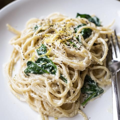 Creamy Lemon Spinach Spaghetti tossed in a glossy, luscious sauce, garnished with fresh lemon zest and shaved Parmesan.  