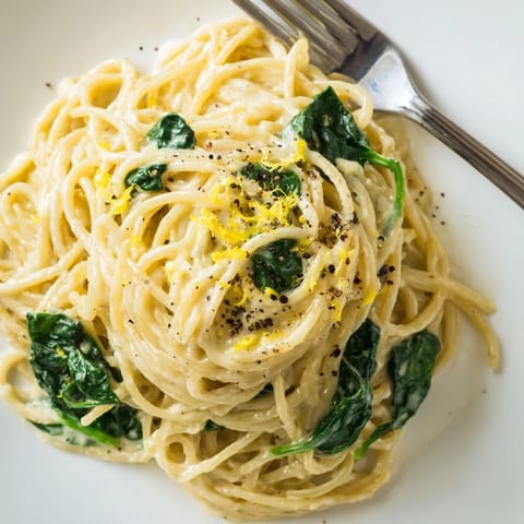 Steaming plate of Creamy Lemon Spinach Spaghetti, featuring vibrant green spinach leaves clinging to silky, al dente noodles.  