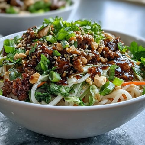 Colorful shredded carrots, cabbage, and fresh herbs top a serving of savory Potsticker Noodle Bowls ready for dinner.