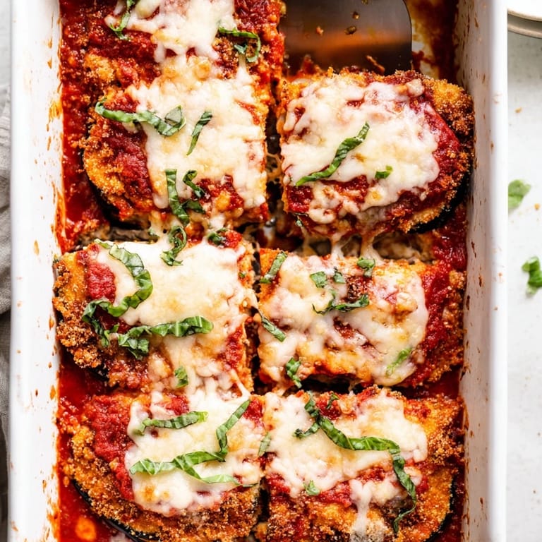 Freshly baked Eggplant Parmesan with golden cheese topping, ready to serve with a glass of wine and crusty garlic bread.