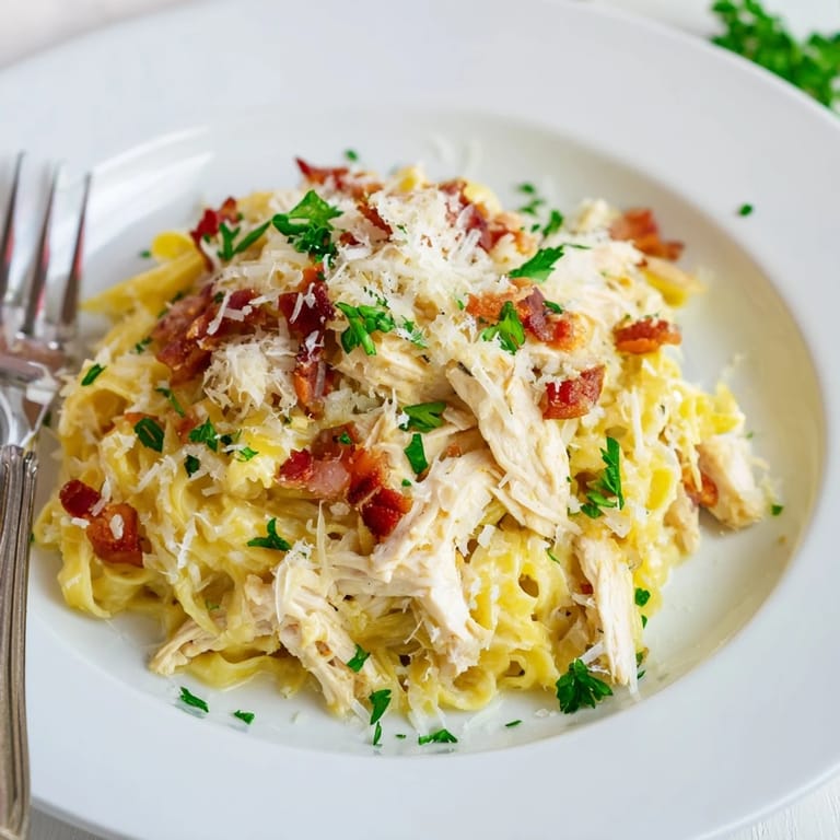 Hearty Chicken Carbonara served in a warm skillet, featuring tender shredded chicken, al dente spaghetti, and a glossy Parmesan egg sauce.
