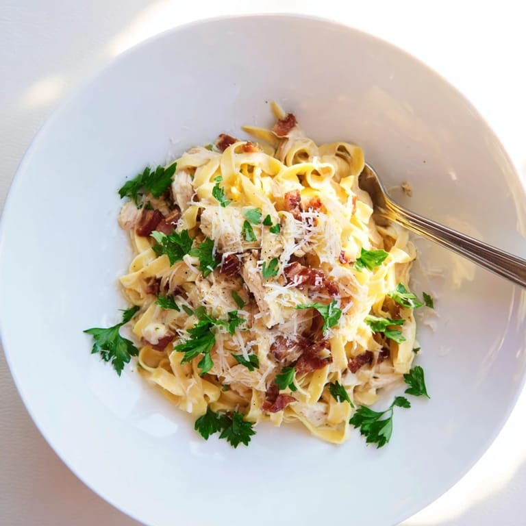 Steaming plates of Chicken Carbonara garnished with fresh parsley, paired with a glass of white wine on a rustic table.