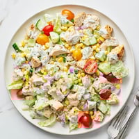 A close-up of Ranch Chicken Chopped Salad in a white bowl, featuring crisp romaine, juicy tomatoes, corn, and creamy dressing.