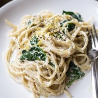 Creamy Lemon Spinach Spaghetti tossed in a glossy, luscious sauce, garnished with fresh lemon zest and shaved Parmesan.  