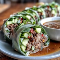 Thai Basil Beef Rolls filled with savory beef, crisp veggies, and fresh herbs on a white plate.