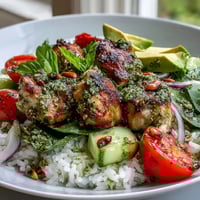 A bowl of Pesto Chicken Bowl with tender marinated chicken and fluffy rice topped with fresh avocado and cherry tomatoes.