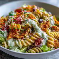 Colorful taco pasta salad with Doritos and avocado ranch, loaded with fresh veggies and crunchy chips in every bite.  