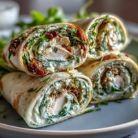 Turkey, cheese, and spinach tortilla pinwheels arranged on a platter, showcasing colorful spirals perfect for party appetizers.  